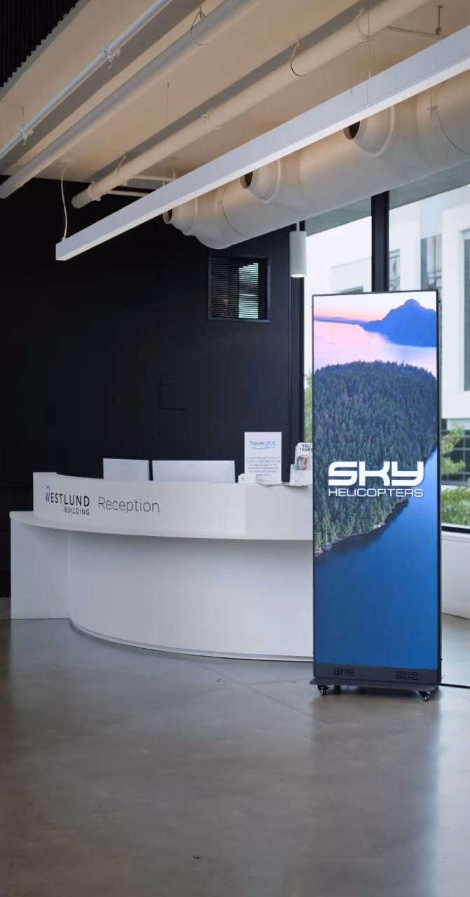 A Sky Helicopters LED totem beside a building reception desk